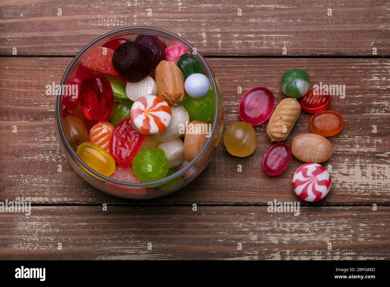 Candies in a jar on a wooden background. Multi-colored caramel. Sweets. Stock Photo