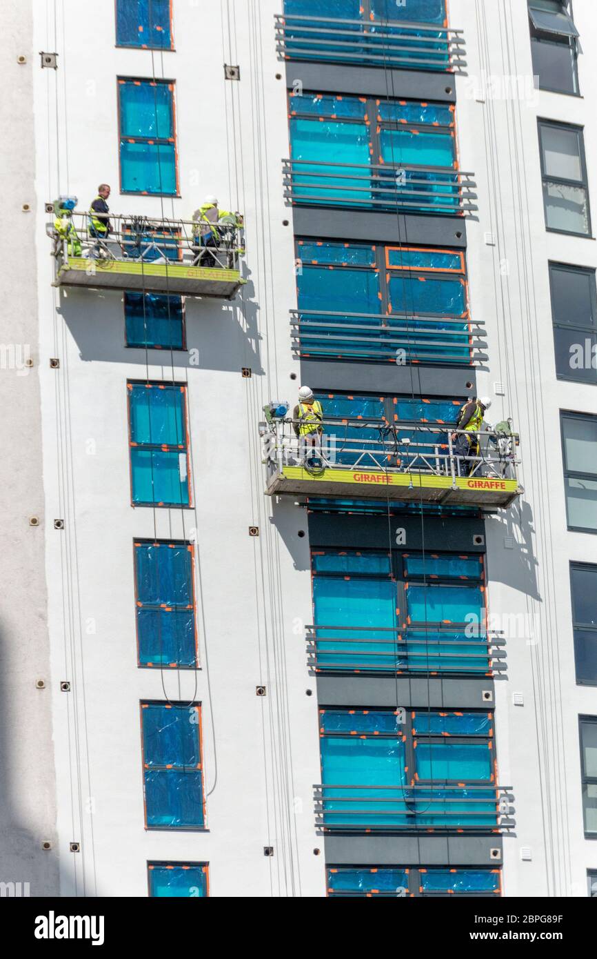 Bristol-May-2020-England-a close up view of workers putting in new windows high up on a high rise building Stock Photo
