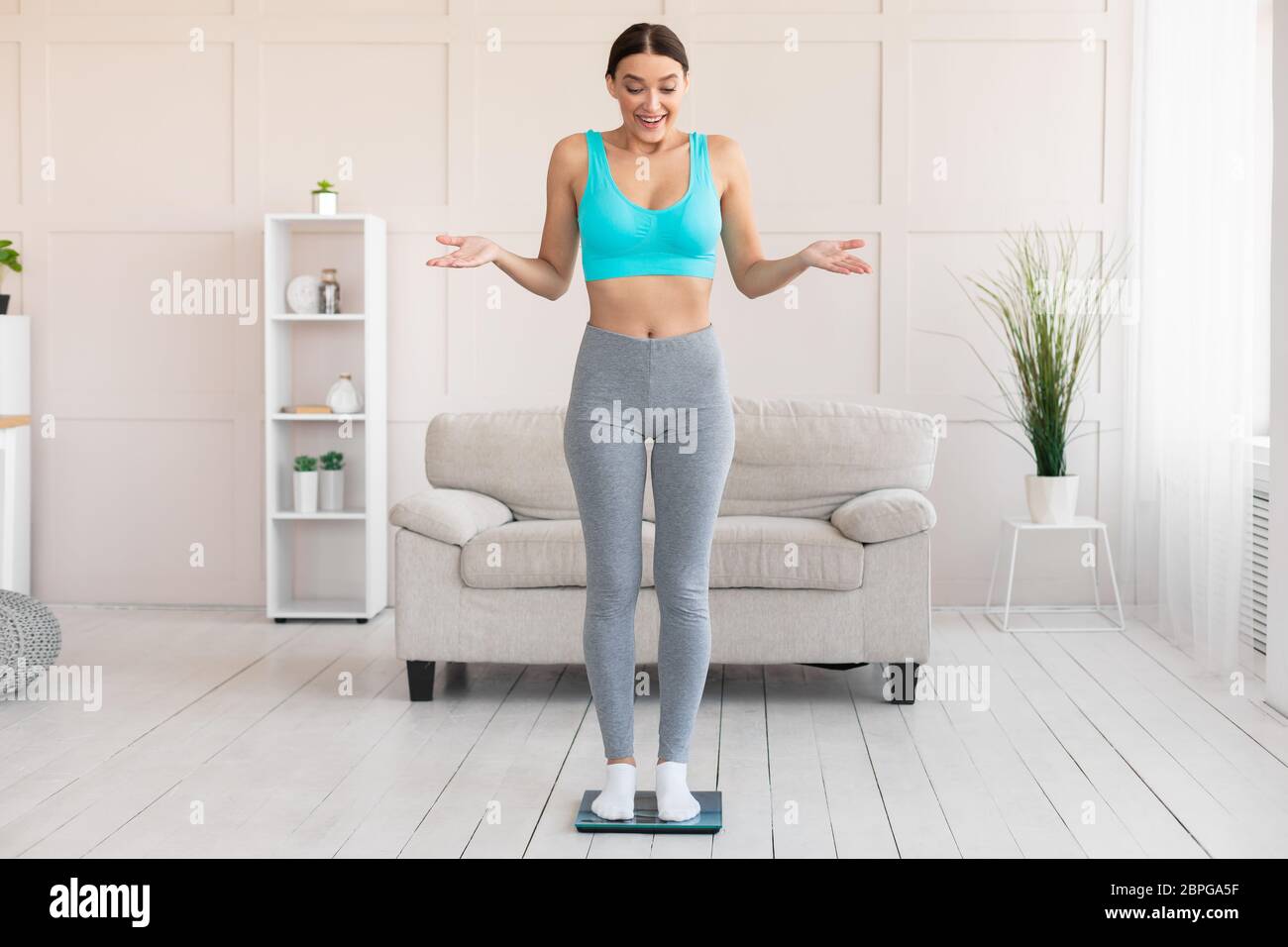 Excited Skinny Girl Weighing Herself On Scales Slimming At Home Stock Photo