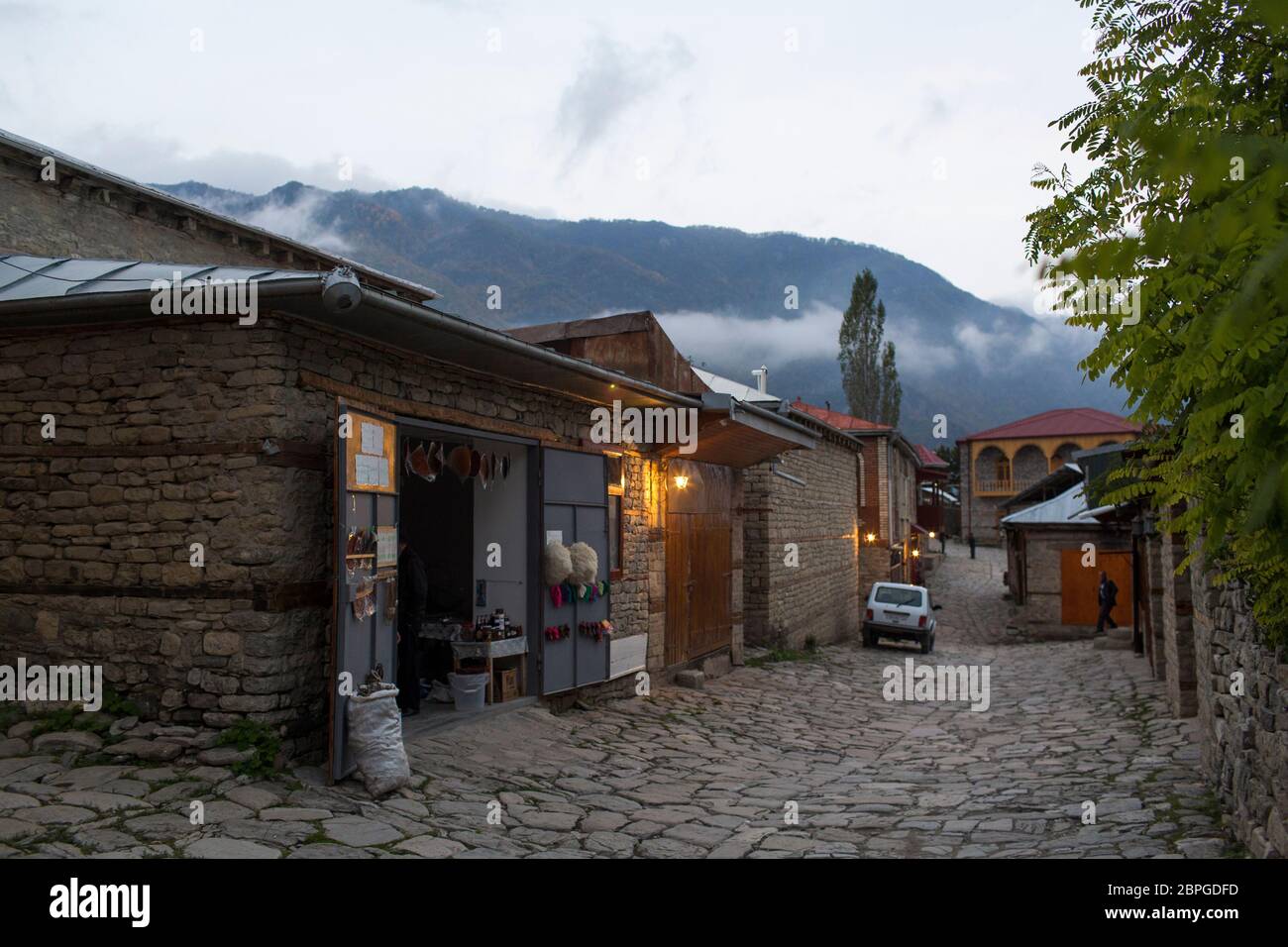 Dusk finds the narrow cobbled lanes lit by sodium street lights as stores and shops get ready to close in Lahic, Azerbaijan. Stock Photo