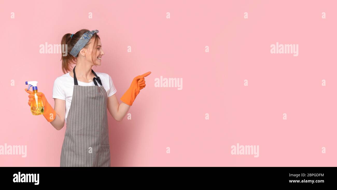 Spring Cleaning Offer. Professional Housemaid In Apron Pointing At Copy Space Stock Photo