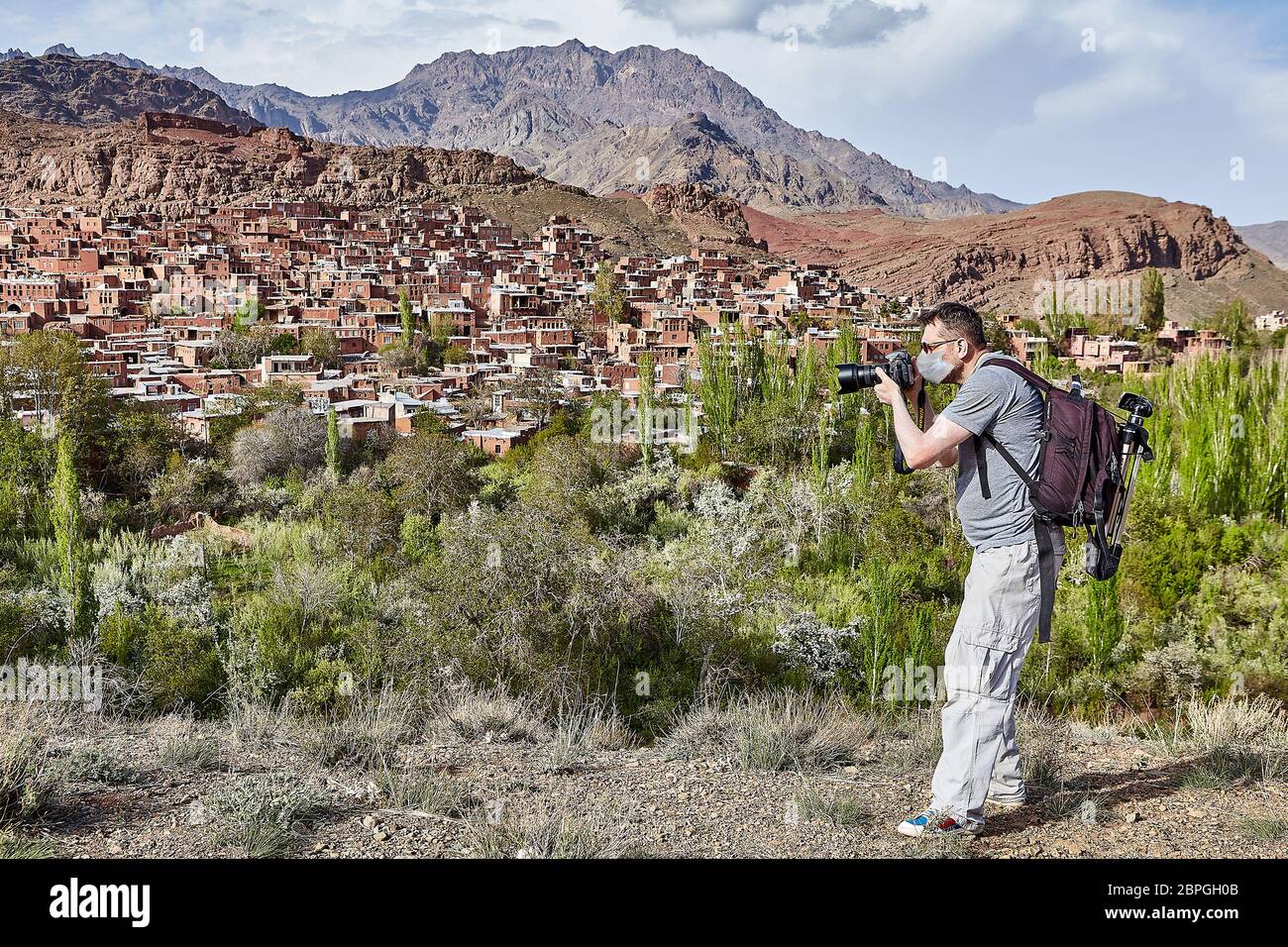 White tourist in a disposable medical mask as a protection in a period of coronavirus pandemic infection covid-19 is making photos in Abyaneh near Kas Stock Photo