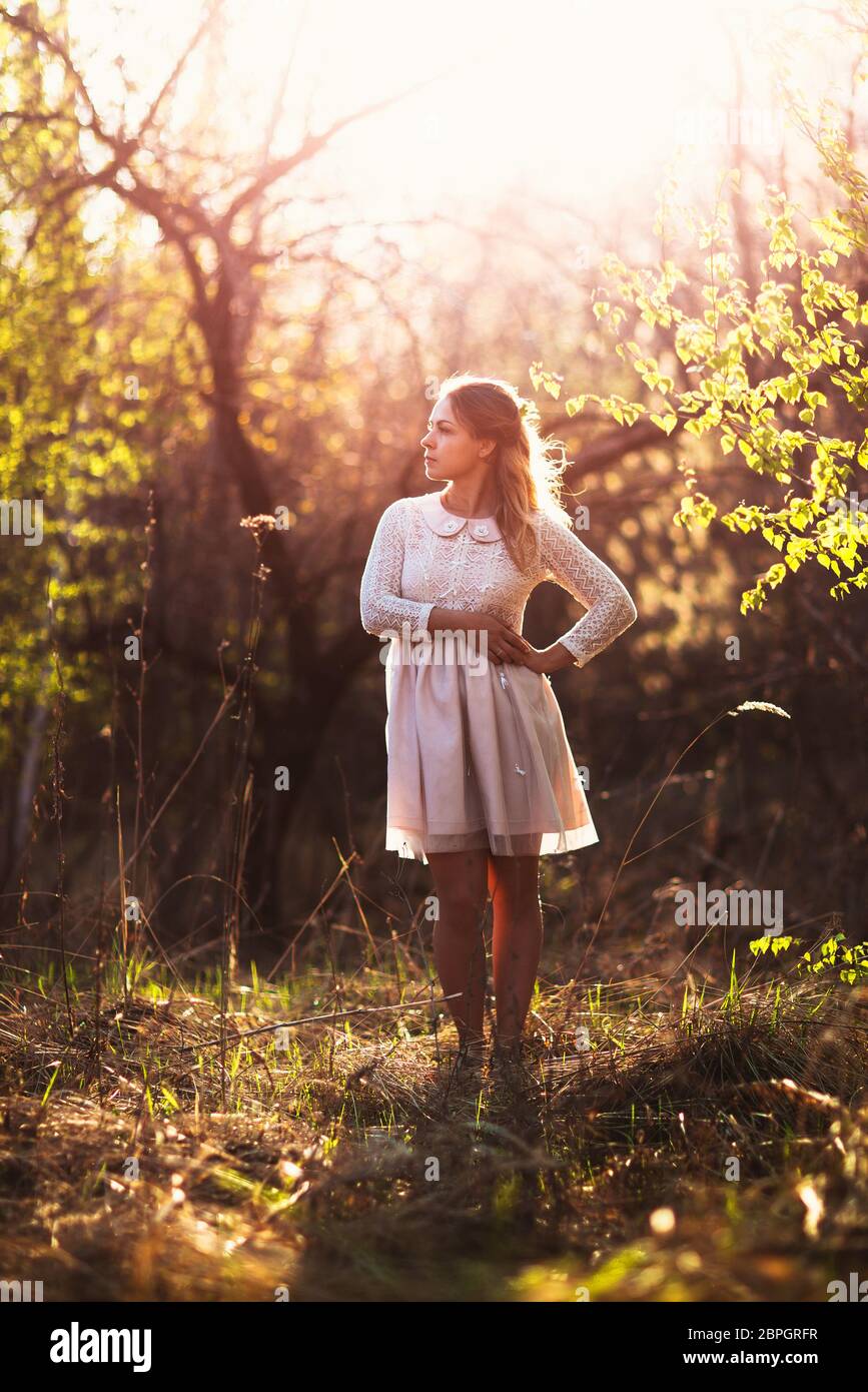 Beautiful girl standing in a field on a sunset background Stock Photo ...