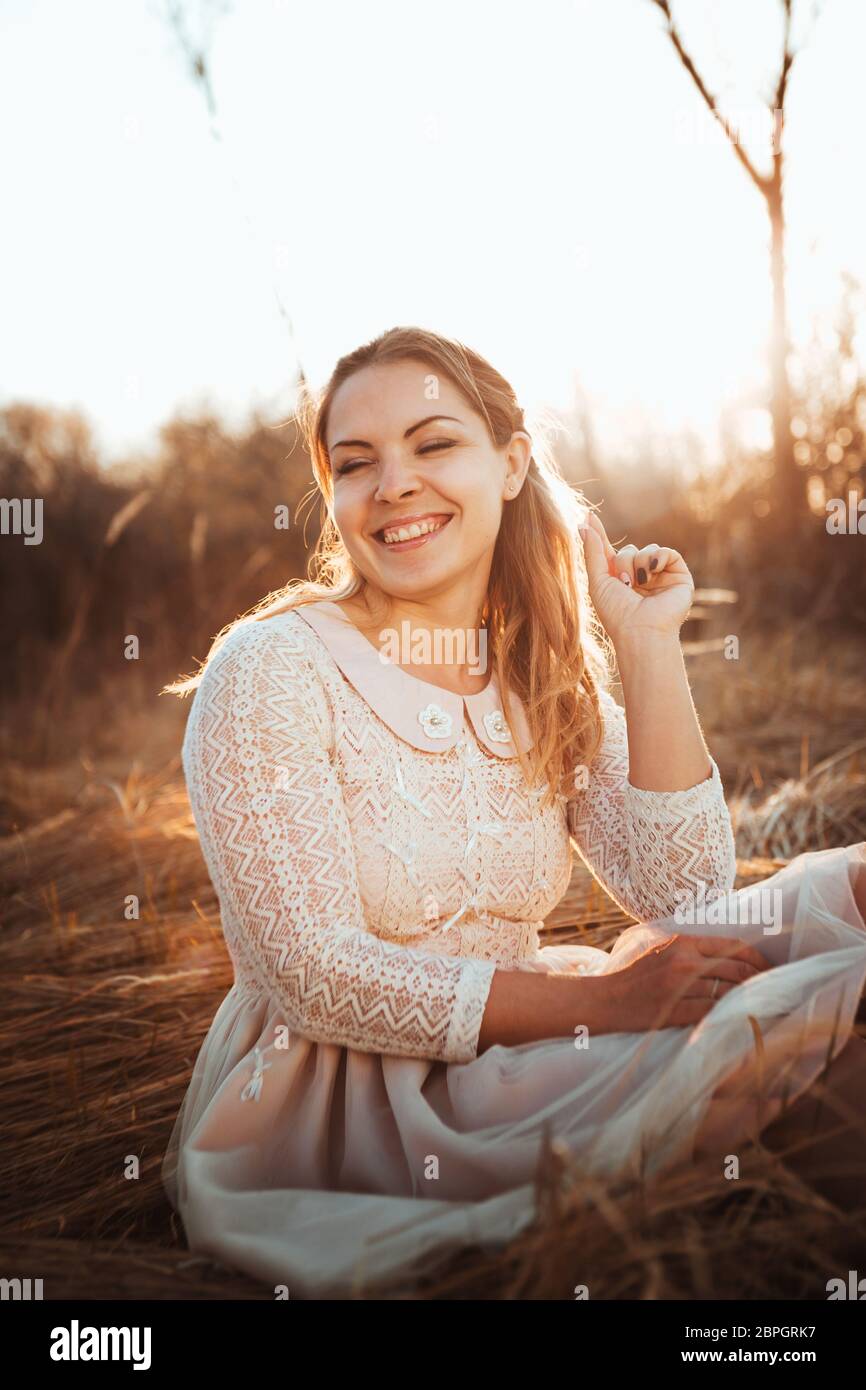 girl is sitting in the field on the sunset background Stock Photo - Alamy
