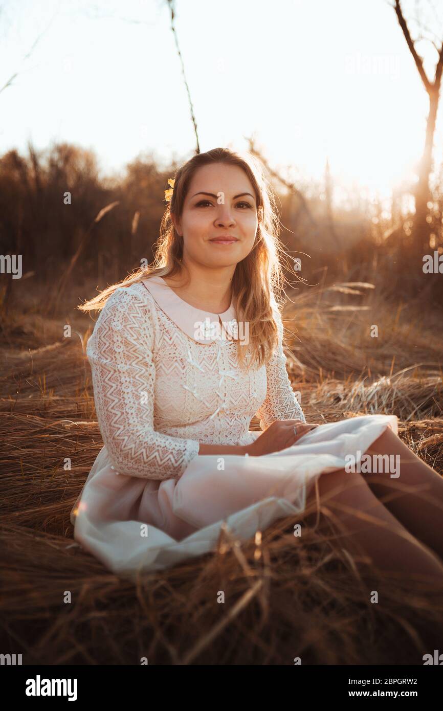 girl is sitting in the field on the sunset background Stock Photo - Alamy