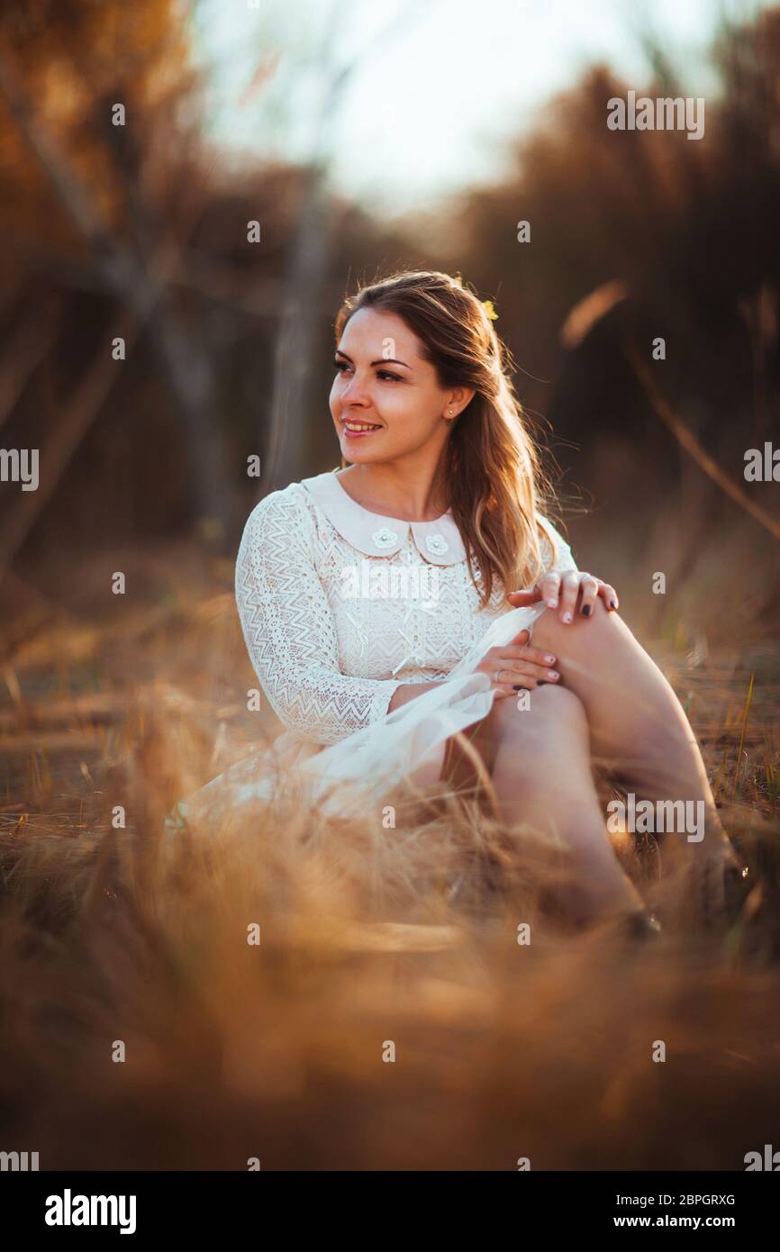 girl is sitting in the field on the sunset background Stock Photo - Alamy