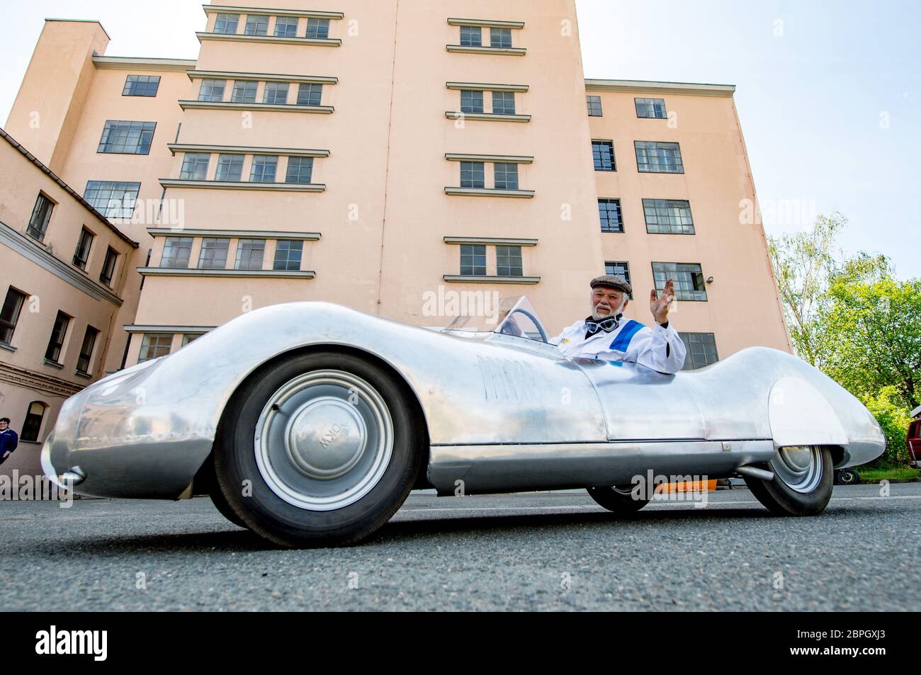 19 May 2020, Saxony, Chemnitz: Frieder Bach, collector and restorer of vintage cars, sits in the last and brand-new DKW F9 sports car in front of the historic high garage in Chemnitz. Bach brought the vehicle to life based on a drawing from 1940, which he had discovered by chance during research for an exhibition in the Museum of Saxon Vehicles. It was the sketch for the last sports car that DKW, at that time under the roof of Auto Union, wanted to build. The vehicle was originally to take part in the Berlin - Rome race in 1938, but the war prevented it from being produced. More than 75 years Stock Photo