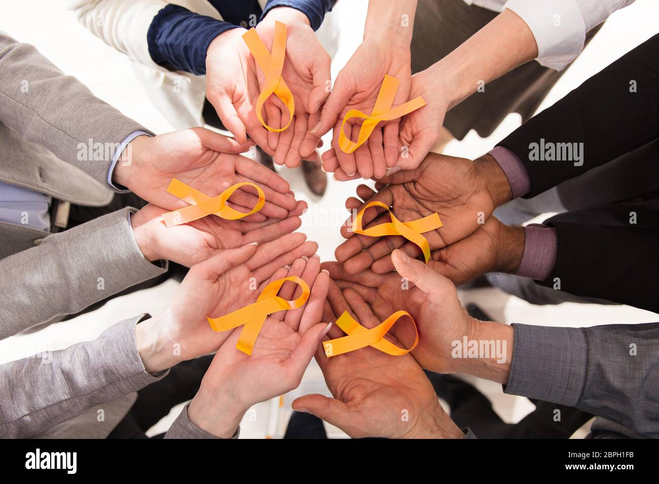 Group Of Businesspeople Holding Teal Ribbons To Support Childhood And Bladder Cancer Stock Photo