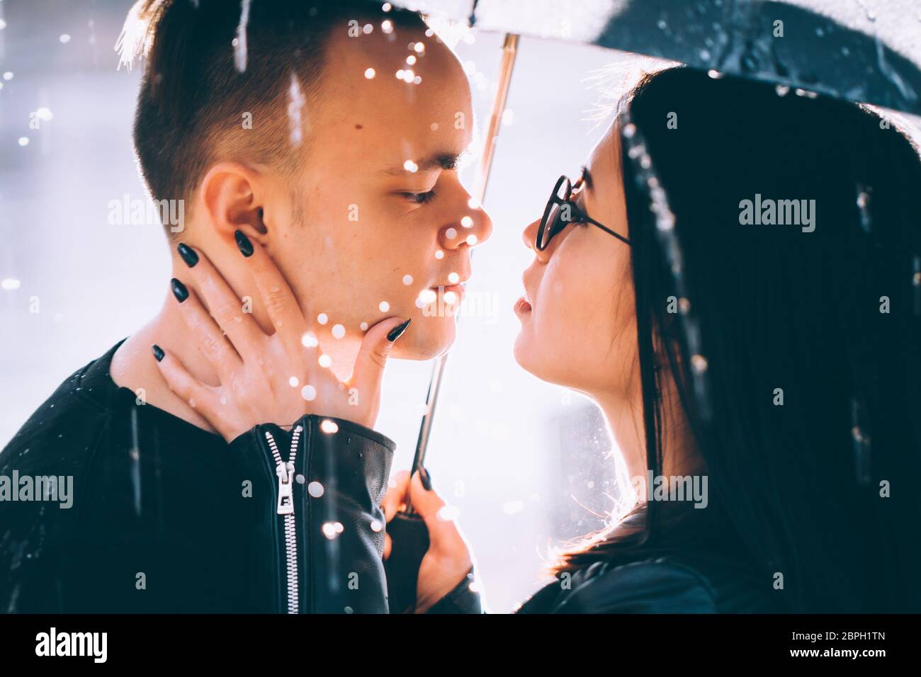 young couple standing under a dark umbrella Stock Photo - Alamy