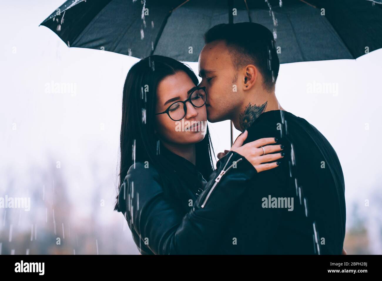 young couple standing under a dark umbrella Stock Photo - Alamy