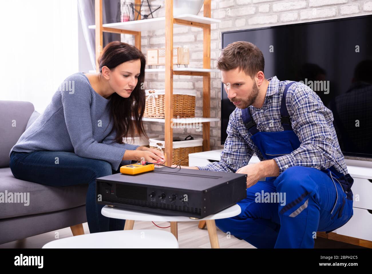 Young Woman Sitting Near Young Male Technician Examining Amplifier With