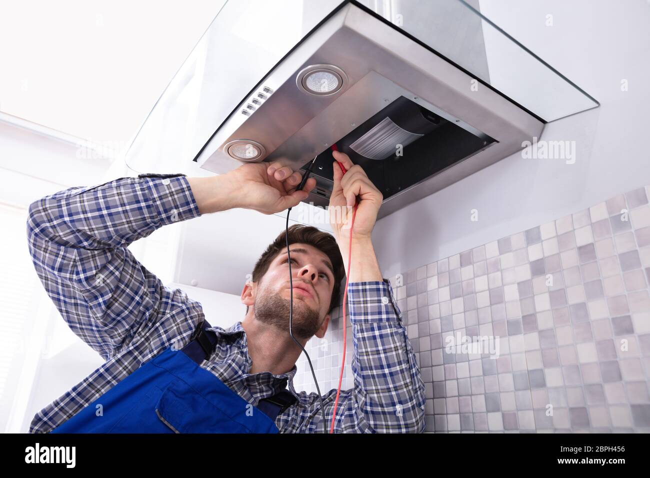 Handyman Checking Kitchen Extractor Filter With Multimeter In Kitchen Stock Photo