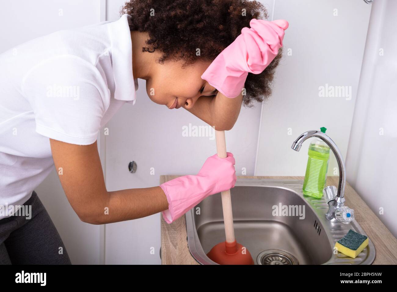 Woman Using Plunger In Kitchen Sink Stock Photo by ©AndreyPopov 110430376