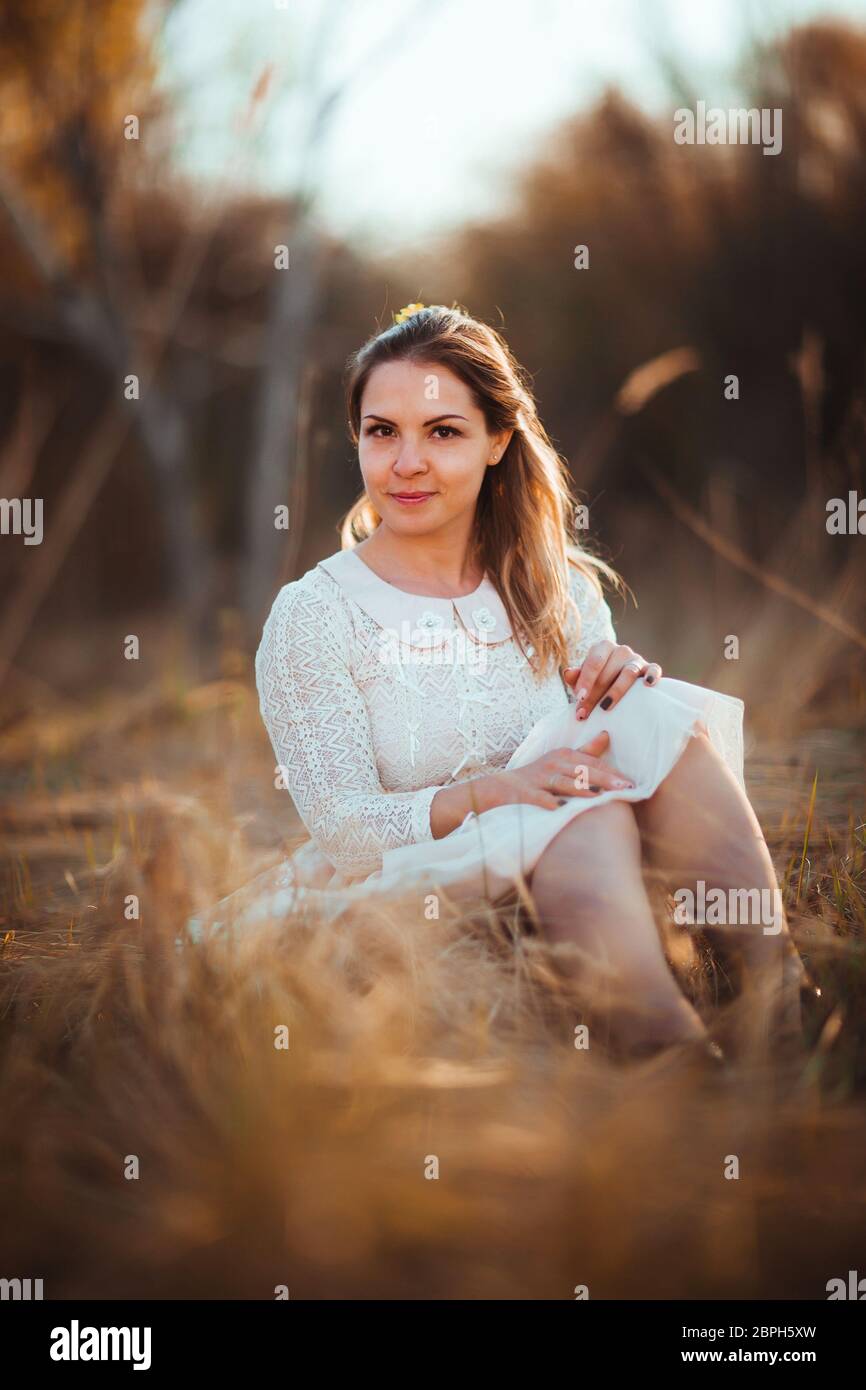 girl is sitting in the field on the sunset background Stock Photo - Alamy