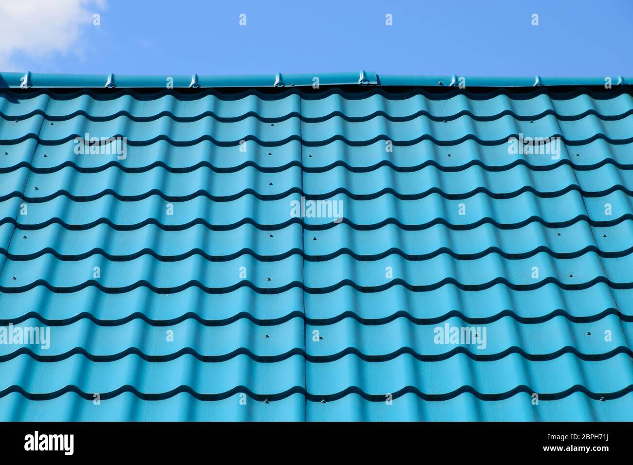 Turquoise metal tiles on the roof of the house. Modern roofing materials Stock Photo