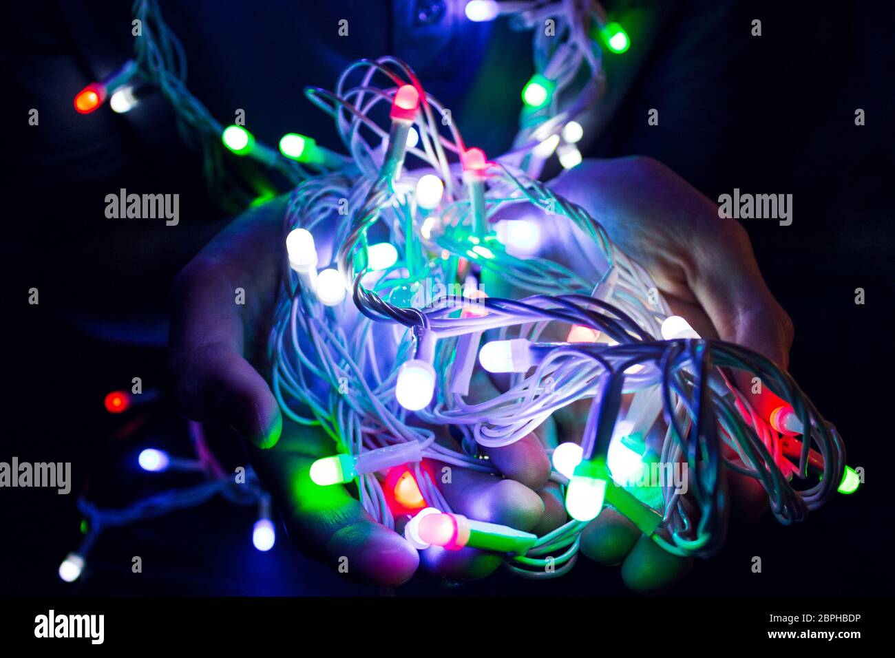 Boy holding Christmas lights in his hands. Holiday spirit idea. Vibrant colors. Shallow deph of field. Lots of colors Stock Photo
