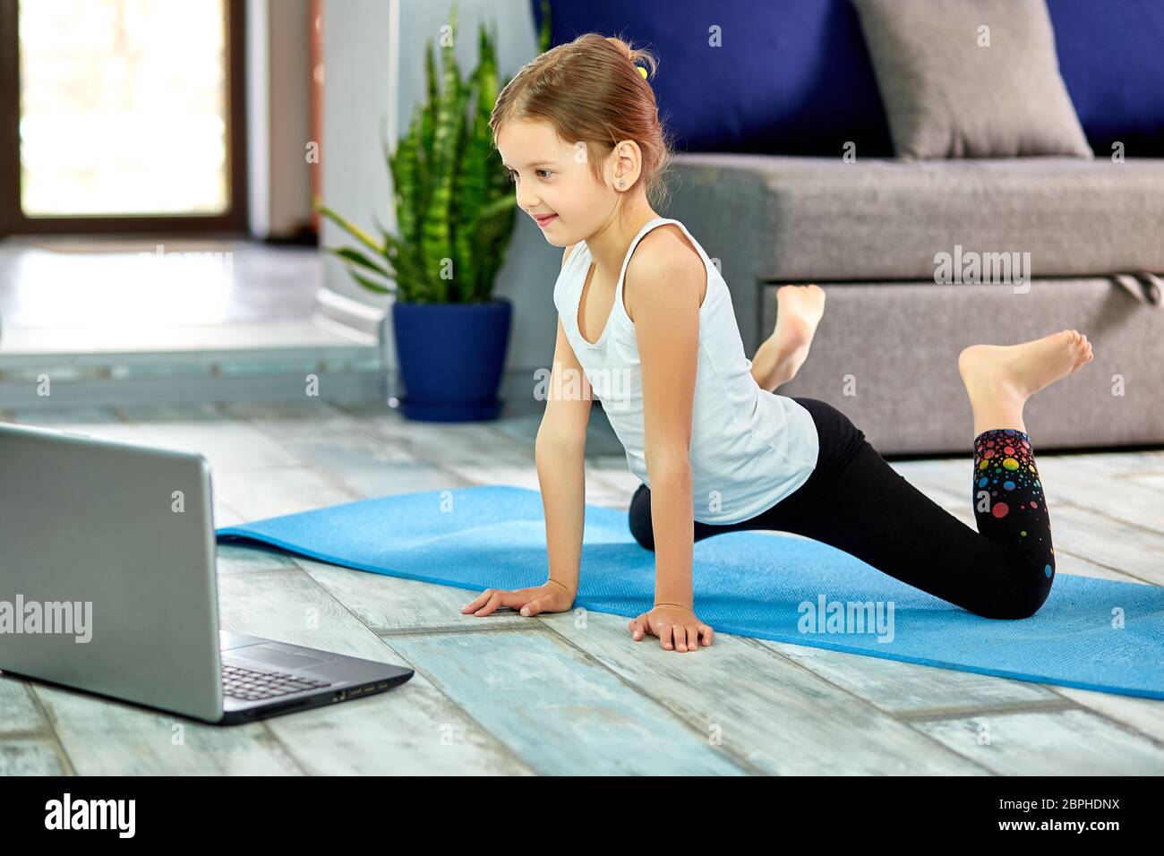 Little girl practicing yoga, stretching, fitness by video on