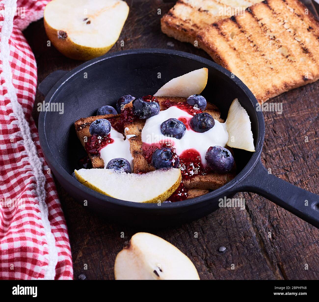 French toast with berries, syrup and sour cream in a black castiron