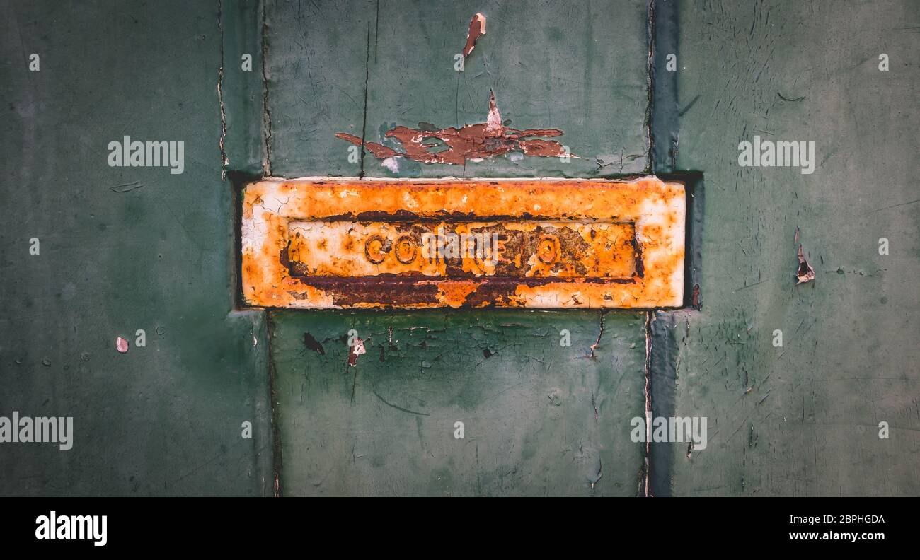 old rusty Portuguese mailbox on a worn wooden door where it is written in Portuguese: mail Stock Photo