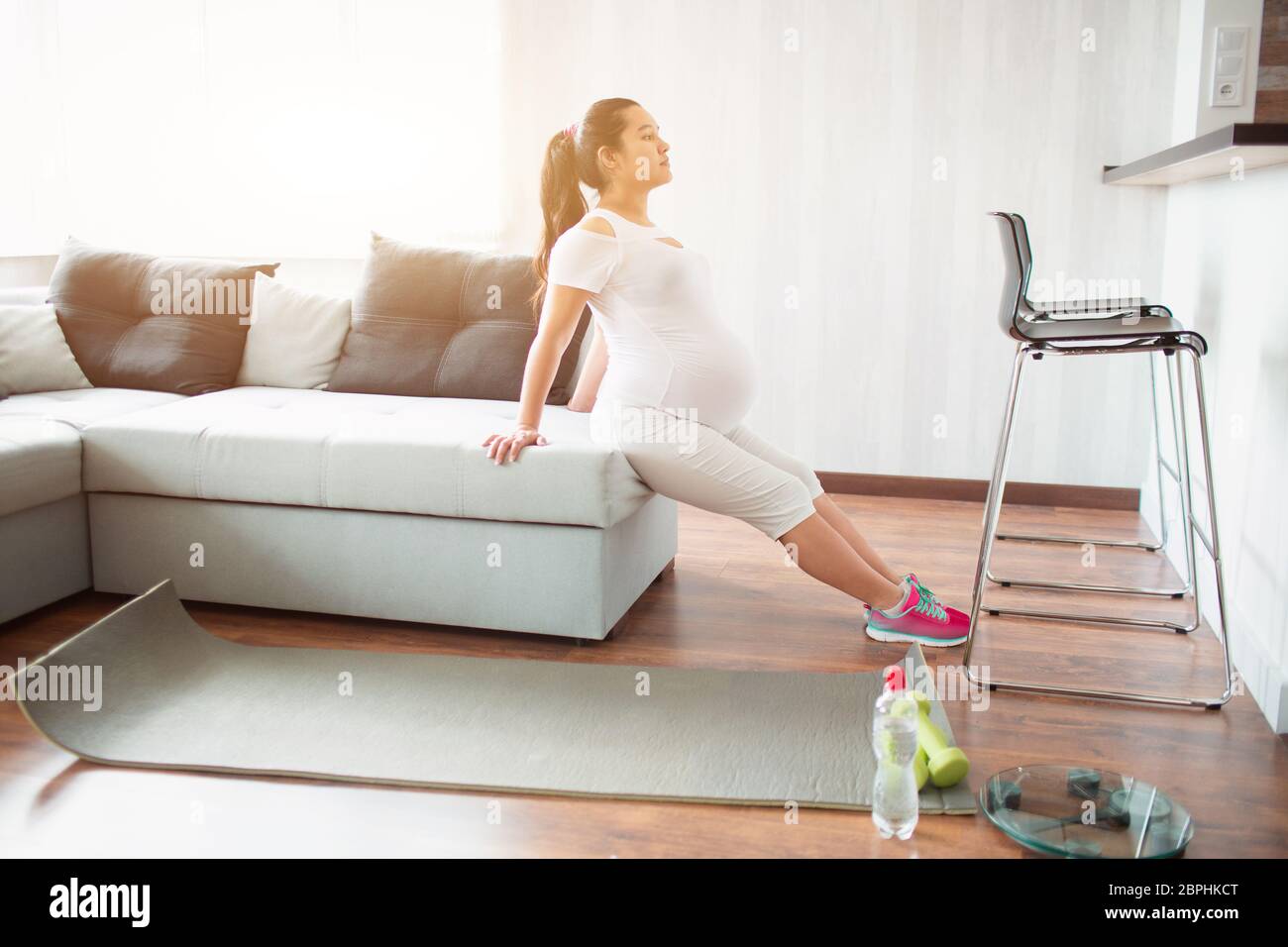 Pregnant woman doing workout at home using a sofa Stock Photo - Alamy