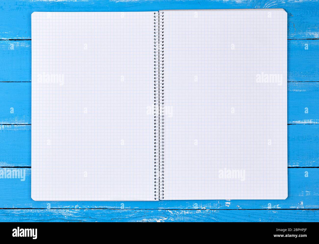 open notebook in a cell on a blue wooden background, top view Stock Photo