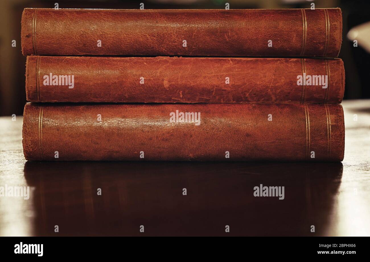Stack of three old vintage brown leather hardcover books on table Stock Photo
