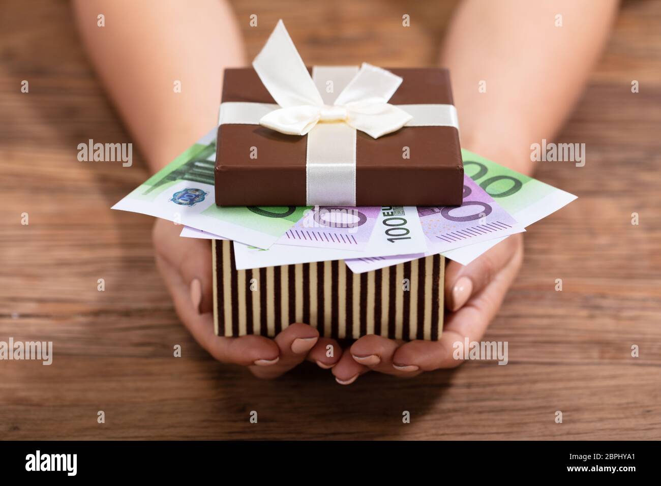 Close-up Of Female's Hand Holding Gift Box Filled With Euro Notes With White Ribbon Bow Stock Photo