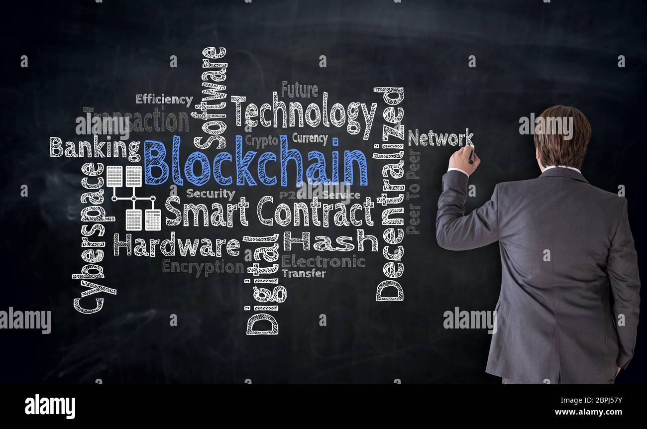 Businessman writes Blockchain cloud on blackboard Concept. Stock Photo