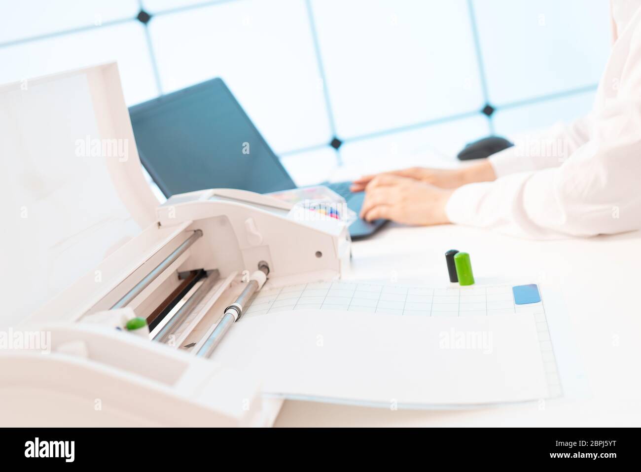 Young woman in the office of the printing company sets up a plotter for printing advertising brochures Stock Photo