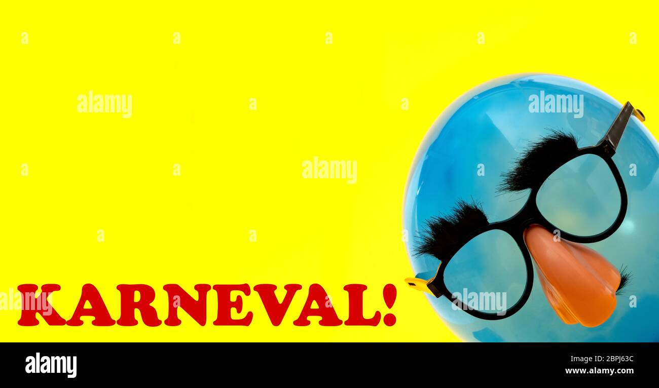Karneval text in german languages means carnival - with blue Ballon with funny mask on yellow background Stock Photo