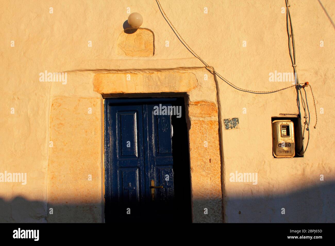 Greece, Serifos island, the door of an old house at Chora with electric meter box in the background. Stock Photo