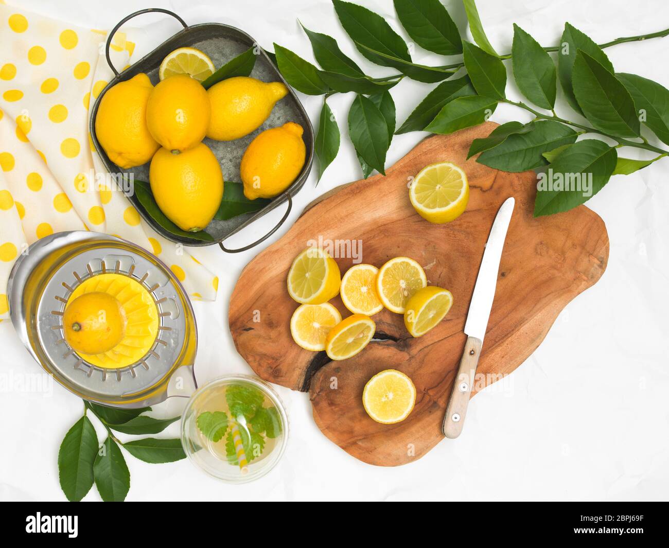 beautiful still life with lemons on white paper background and wooden board and knife Stock Photo