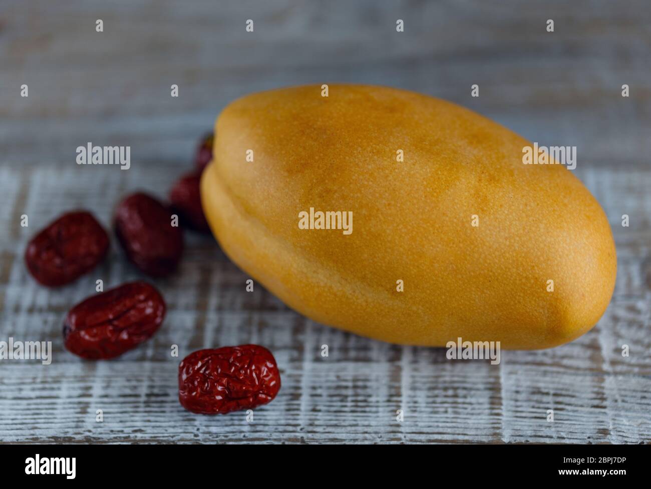 Ripe yellow mango fruit on wooden surface with dates Stock Photo