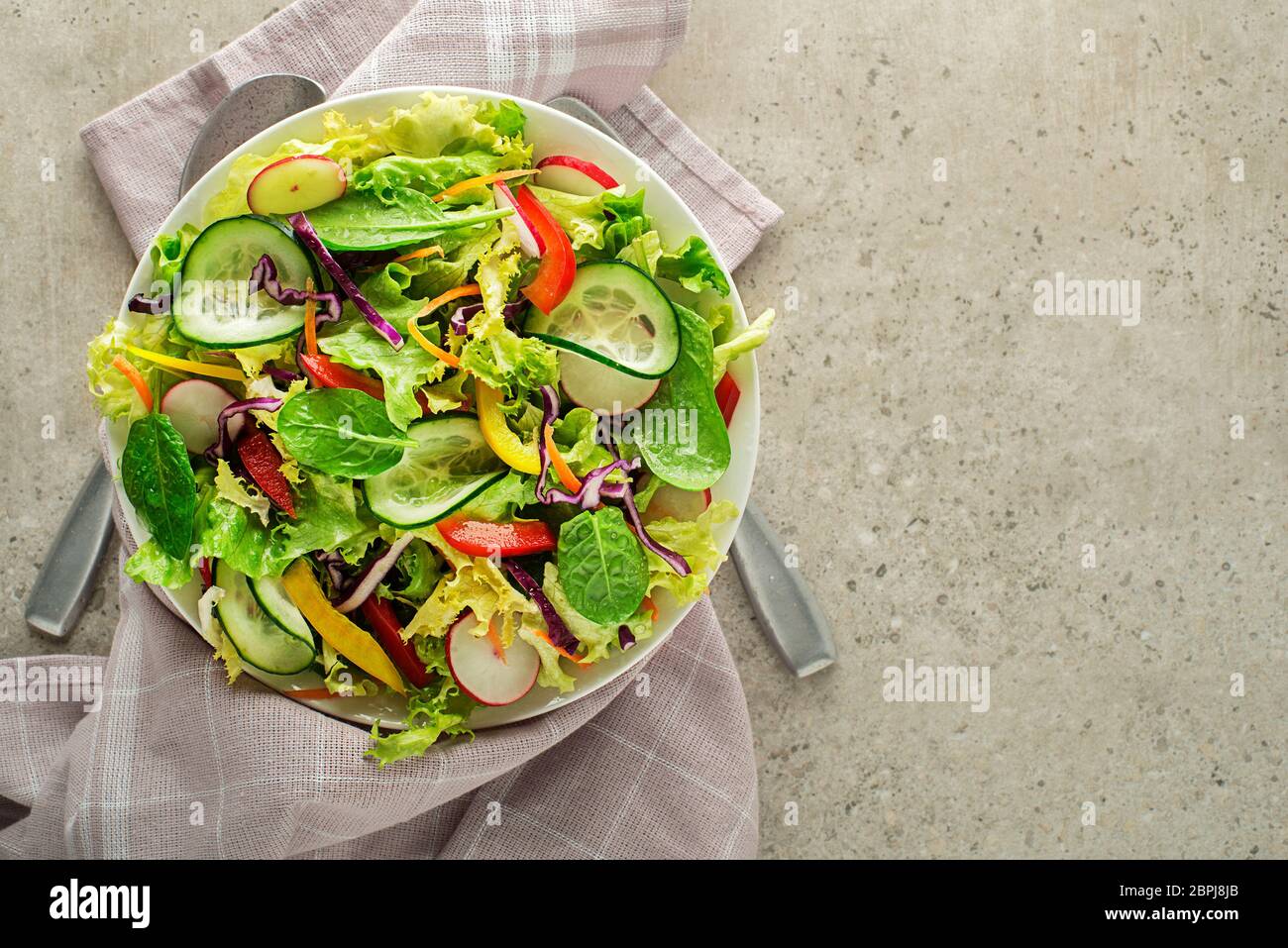 Green lettuce salad with fresh mixed vegetables on grey table background Stock Photo