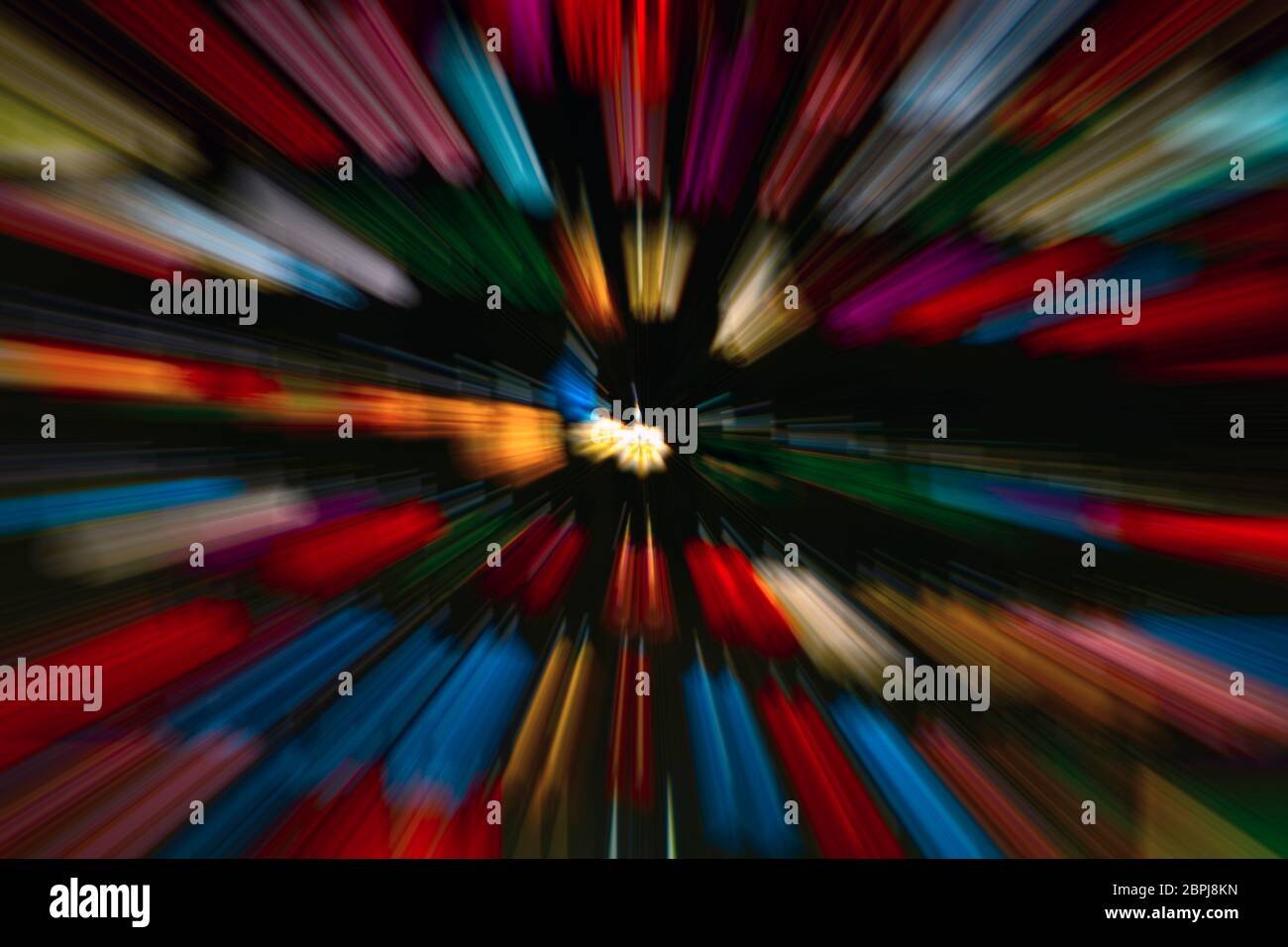 Background image with central zoom motion blur in slightly tilted plane, vivid color strokes on black. Stock Photo