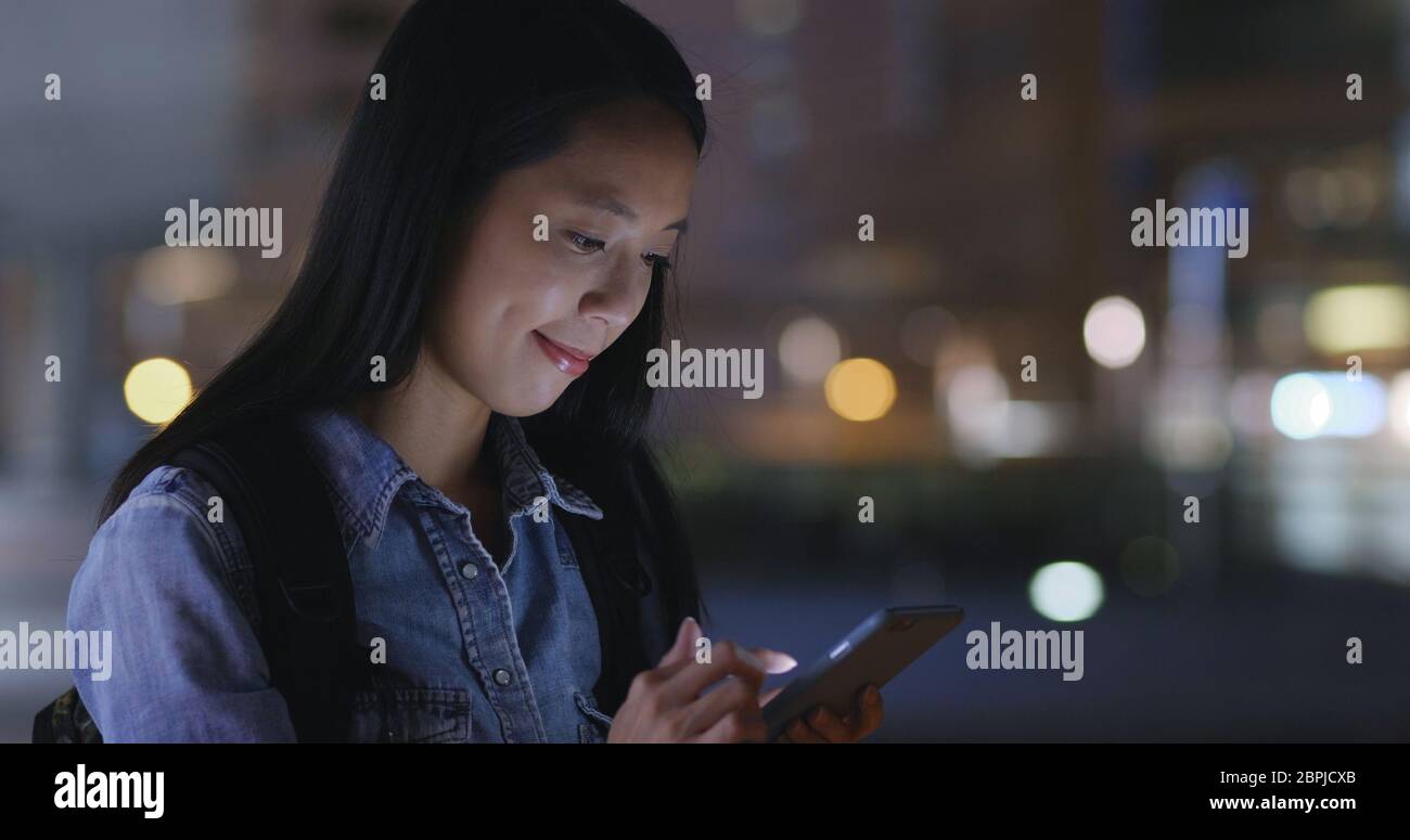 Woman look at mobile phone in Hong Kong city at night Stock Photo - Alamy