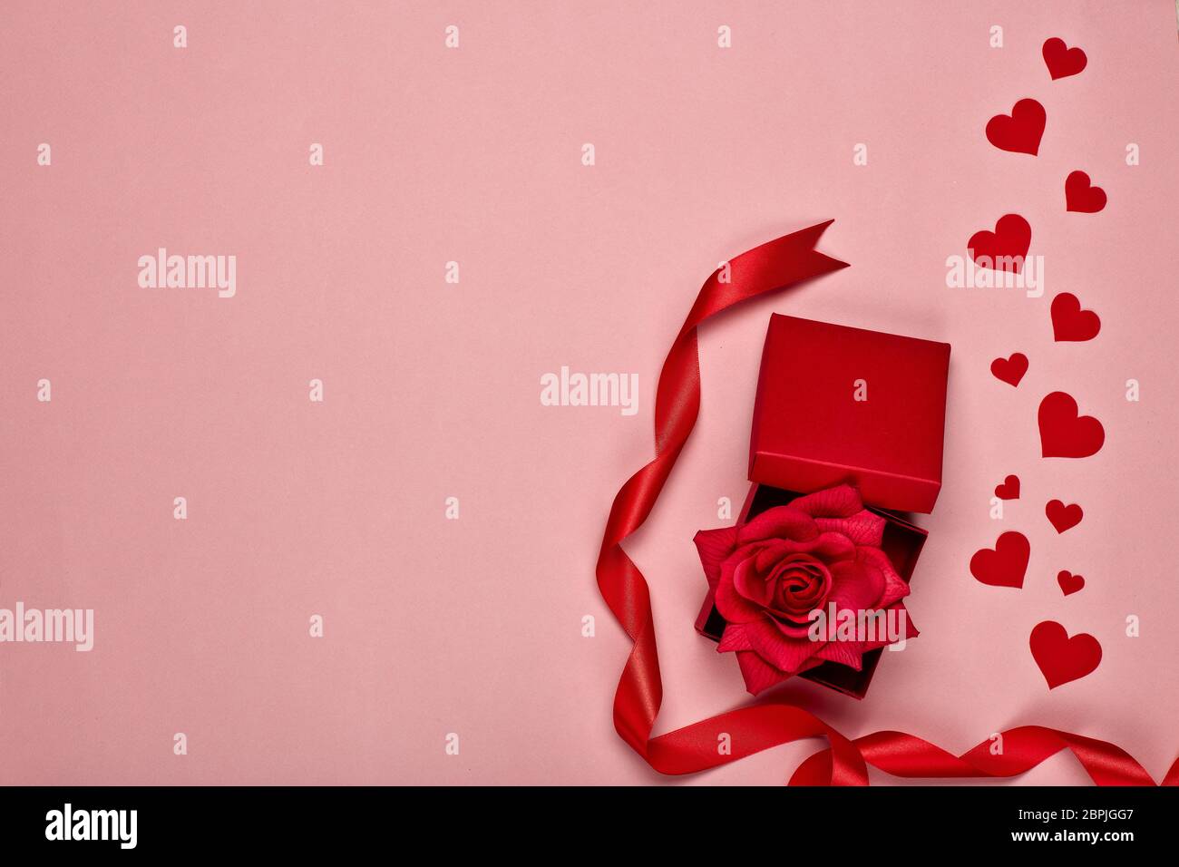 Red decorative hearts and gift box with rose on a pink background with ...