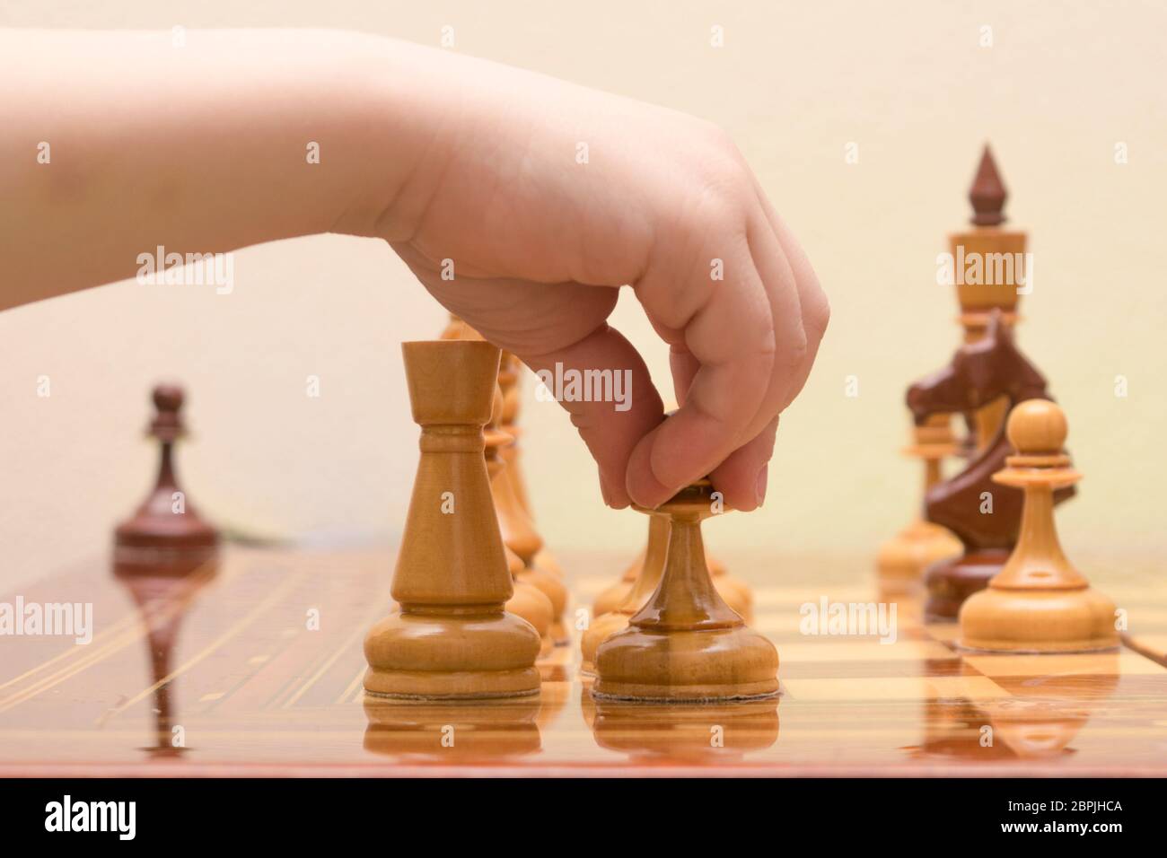 the children's hand puts a chess figure on the game field Stock Photo