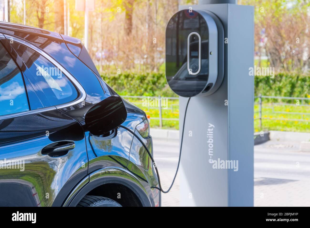 Refueling for cars e-mobility. Charging an electric car at hybrid engine gasoline and electricity repair shop service garage Stock Photo
