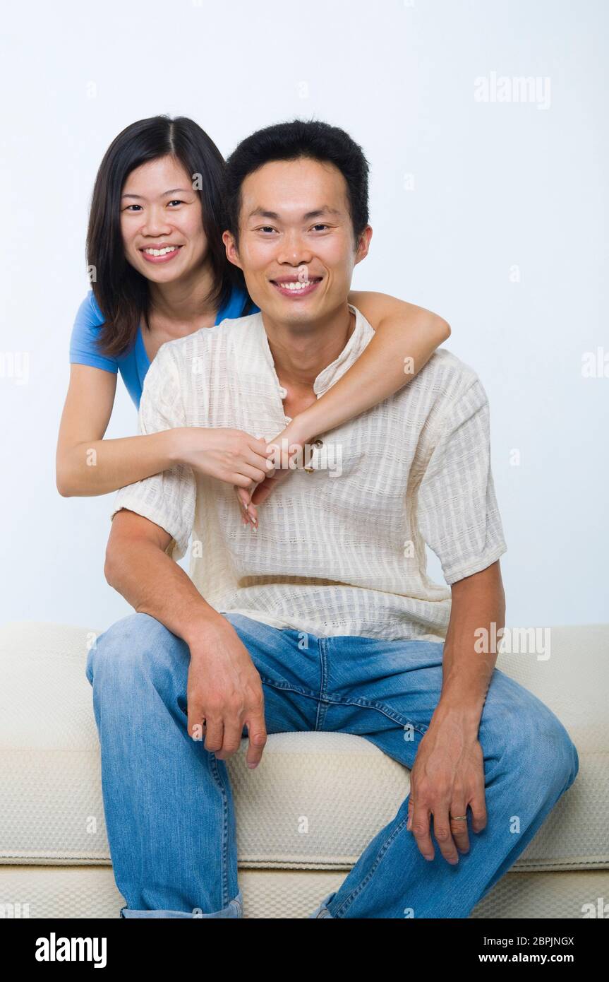 Young Asian couple sitting on sofa with smiling face, on white ...