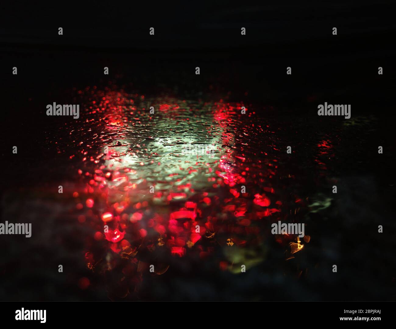 Dramatic red and green raindrops on rainy surface background Stock Photo