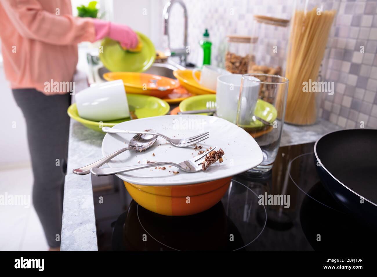Close-up Of A Woman Washing Dishware With Sponge And Utensil On Kitchen Counter Stock Photo