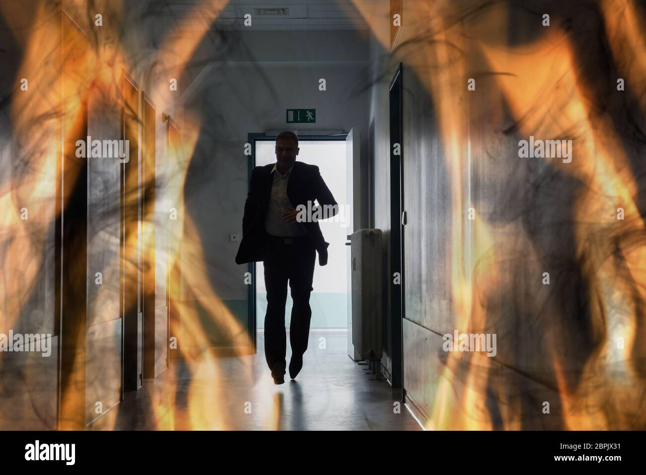 Silhouette Of Person Running Out Of Fire Escape On Corridor Of Building Stock Photo