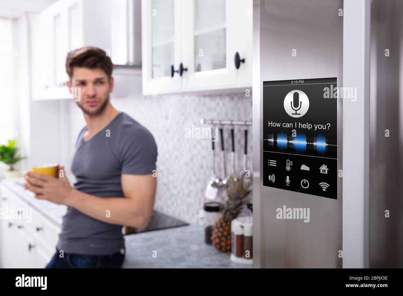 Man Standing Near Oven With Voice Recognition Function In Kitchen Stock Photo