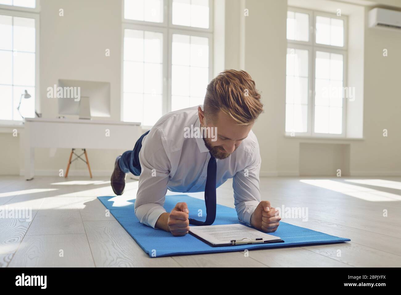 Businessman doing abs strap exercises while lying in the office. Stock Photo