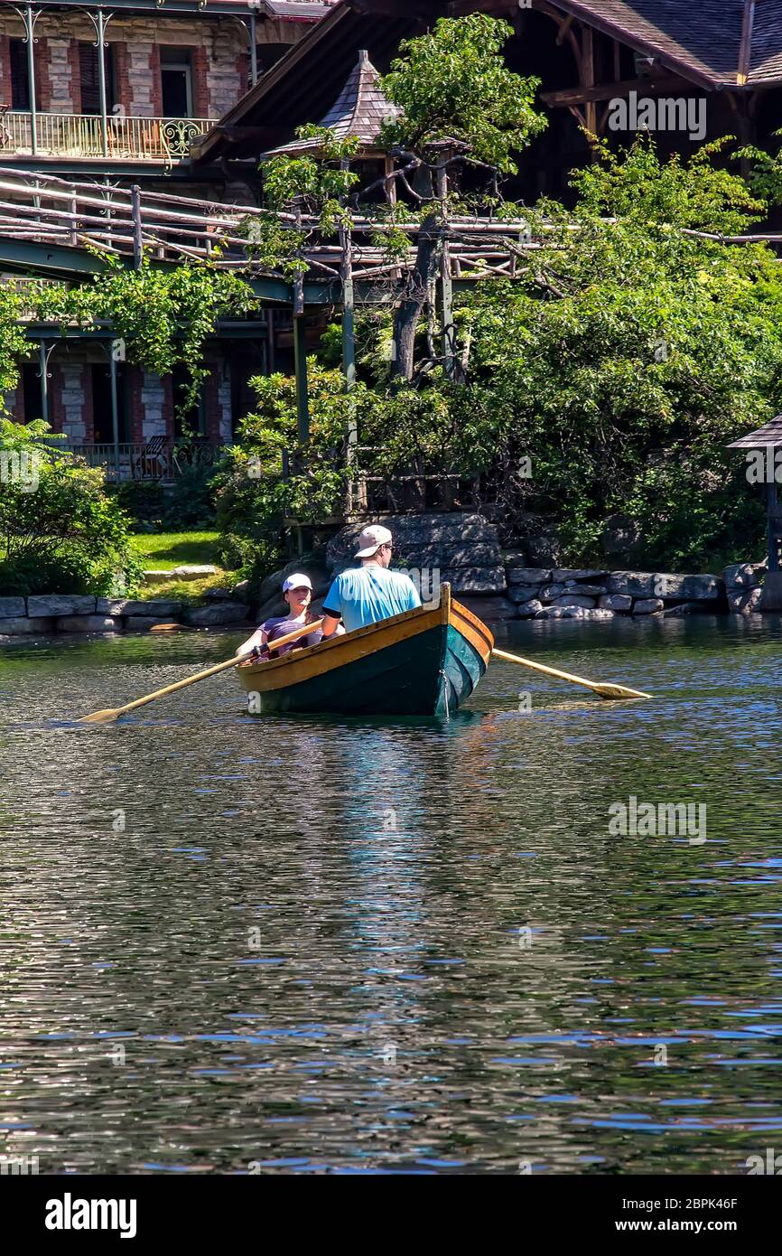 New Paltz, New York - June 22, 2014:  Young couple navigate a row boat in Lake Mohonk, a Victorian style hotel nestled in the Shawangunk Mountain Ridg Stock Photo