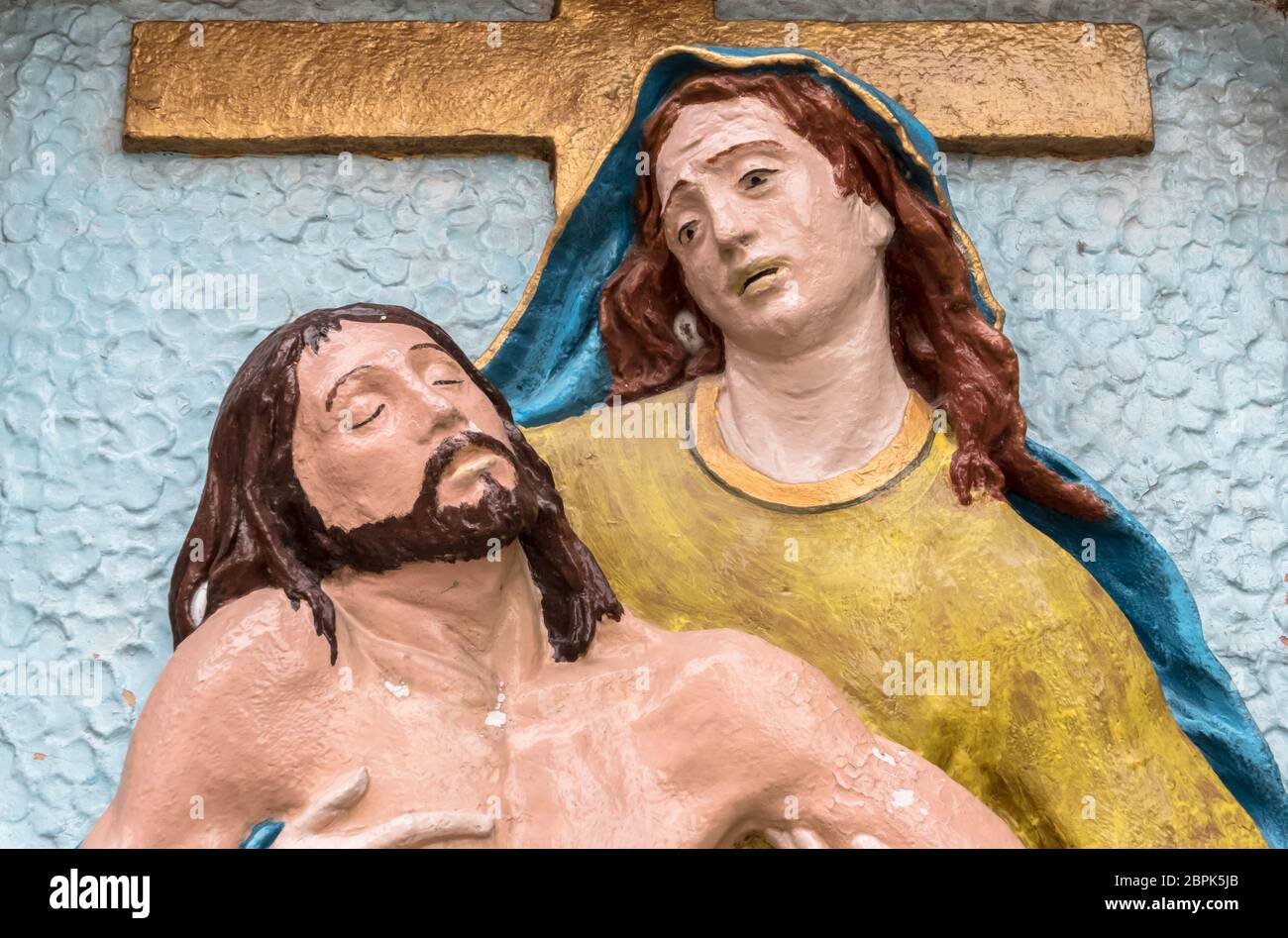 Religious stone statue in color representing The Pity of Michelangelo. Mary mother holding Jesus Christ on her lap after the Crucifixion. Stock Photo