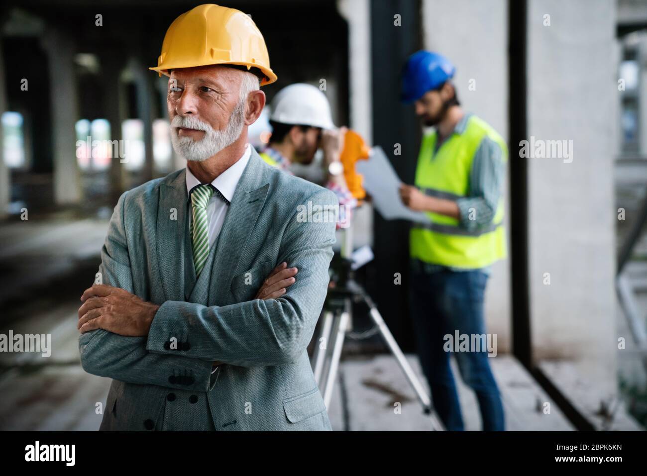 Two satisfied engineers talking at building site with construction structure in background Stock Photo