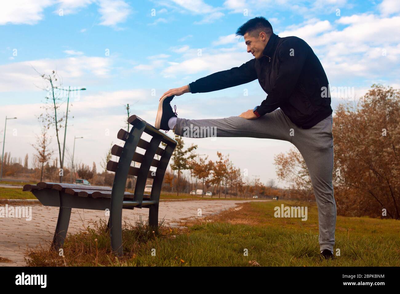 The sporty man is stretching on bench after jogging outdoors in park Stock  Photo - Alamy