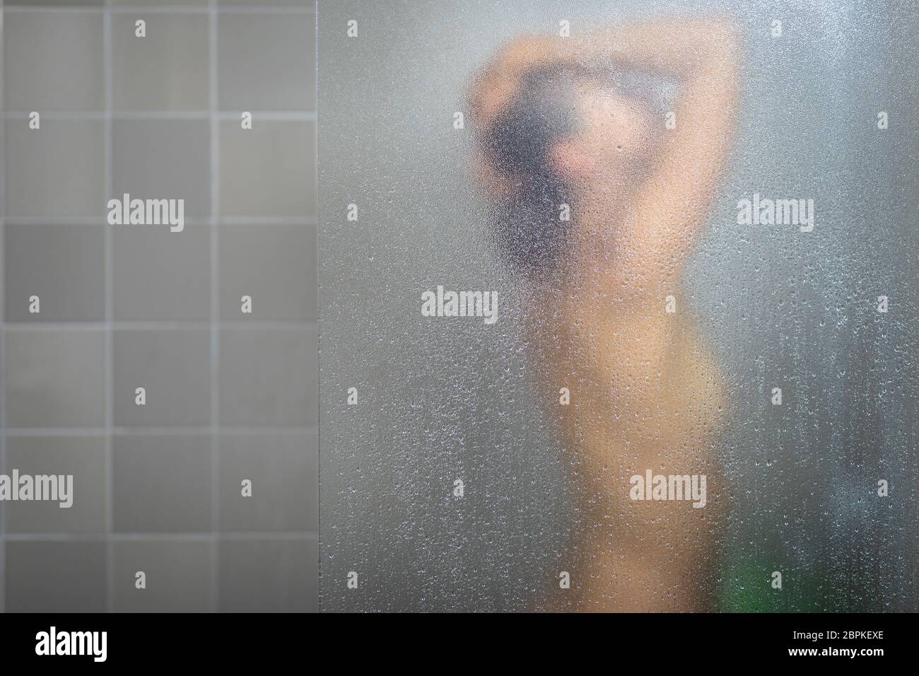 Woman taking a long hot shower washing her hair in a modern design